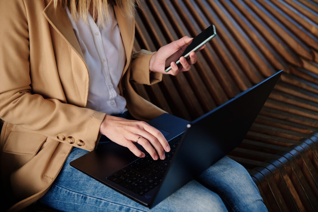 Woman working on laptop and on phone.